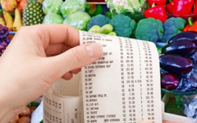 hand holds the check from supermarket against vegetables and fruit
